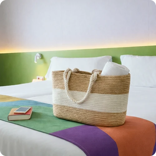Weidenkorb mit Handt&uuml;chern und Telefon auf dem Bett in einem Hotelzimmer