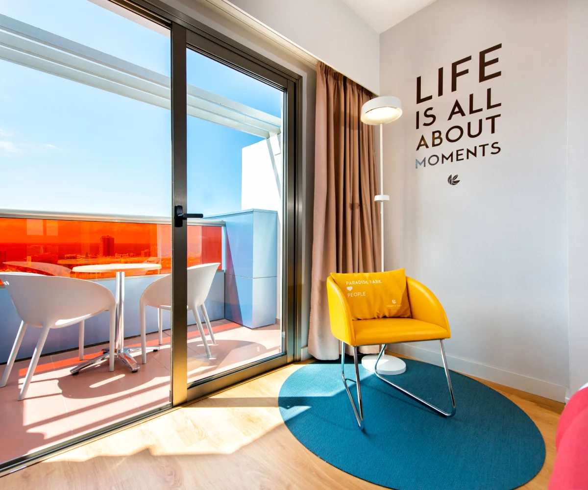 B&uuml;ro mit gelbem Sessel, Schiebefenster und Wand mit Schild "Life is all about moments"